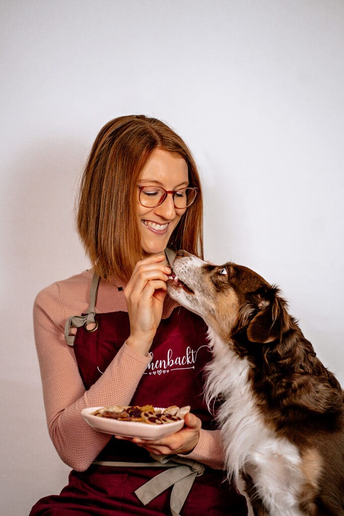 Frau gibt ihrem Hund ein Leckerli.